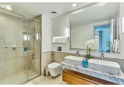 a bathroom with a sink and a toilet and a mirror at bnbmehomes - Elegant Pool View - 2BR Apartment - 607 in Dubai
