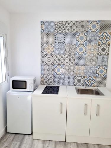 a kitchen with white cabinets and a tile wall at Apartamentos T5 Valencia in Torrent