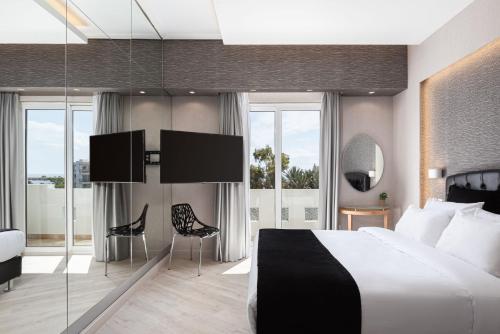 Kreoli Suites Glyfada في أثينا: غرفة فندقية بسرير كبير وجدران زجاجية