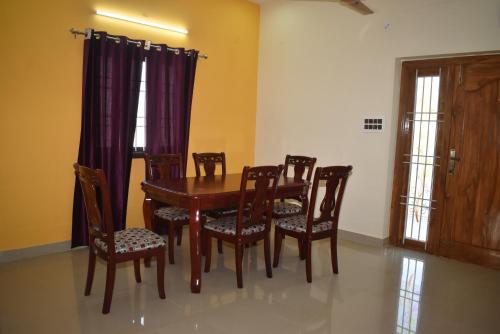 a dining room with a wooden table and chairs at Private 4 BHK Villa with WiFi, Swimming Pool, BBQ in Chennai