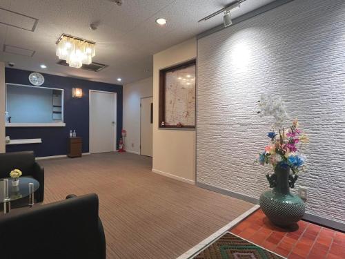 a lobby with a waiting room with a vase of flowers at Business Hotel Azuma in Hanno