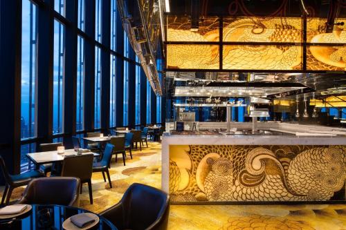 a restaurant with tables and chairs and a wall of windows at The Westin Jakarta in Jakarta