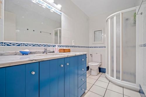 a bathroom with blue cabinets and a shower and a toilet at Hauzify I Apartament Capellans in Salou