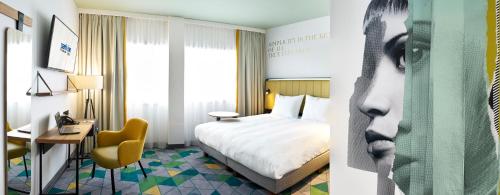 a hotel room with a bed and a desk and a bed and a room at Park Inn By Radisson Hasselt in Hasselt