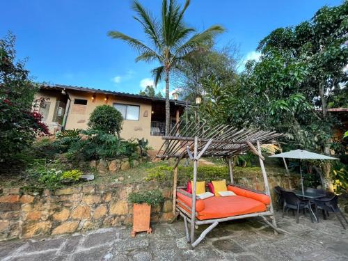 a patio with an orange couch and an umbrella at Hotel Casas de Campo El Ciruelo in San Gil