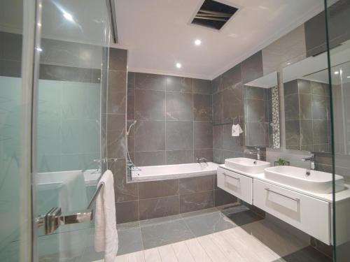 a bathroom with two sinks and a tub and a shower at Masingita Towers Hotel and SPA in Johannesburg