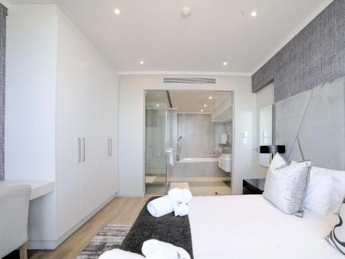 1 dormitorio con 1 cama blanca grande y baño en Masingita Towers Hotel and SPA, en Johannesburgo