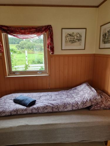 a bed in a room with a window at Warm and cozy cottage, Great location in Kvaløya