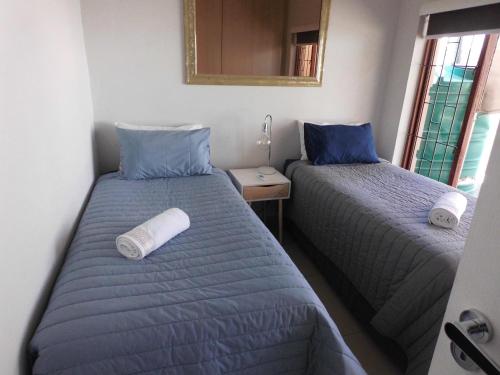 1 dormitorio con 2 camas y espejo en la pared en The Cottage en Krugersdorp