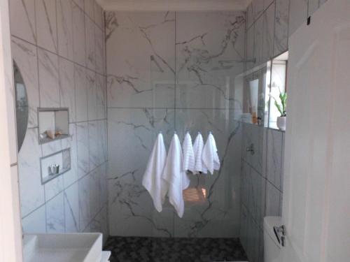 a bathroom with white towels hanging on a wall at The Cottage in Krugersdorp