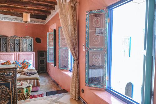een slaapkamer met oranje muren en een groot raam bij Héritage Lalla Aicha Hotel & Spa in Marrakesh