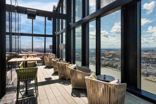 ein Restaurant mit Stühlen und Tischen auf der Aussichtsplattform eines Wolkenkratzers in der Unterkunft Melia Vienna in Wien