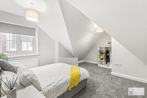 a white bedroom with a bed with yellow sheets at Elegant 5-Bed House with ample parking in Smisby