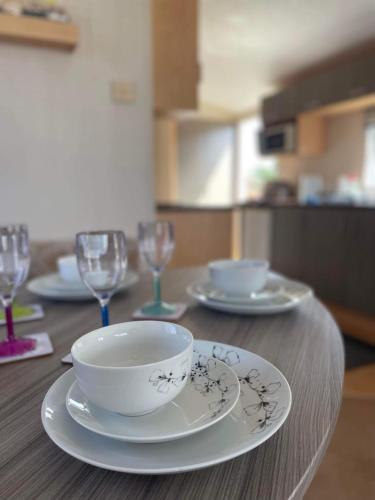 a wooden table with a bowl and plates and glasses at The Willerby Vacation in Leysdown-on-Sea