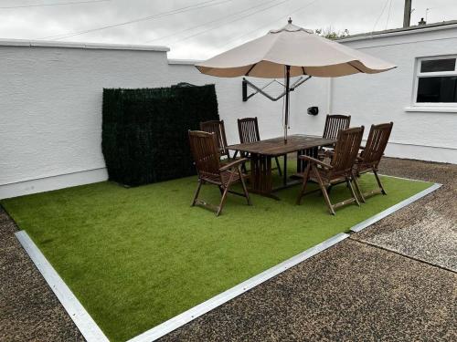 a patio with a table and chairs and an umbrella at 4-Bed House - Sea View Garden Parking Wifi in Portstewart