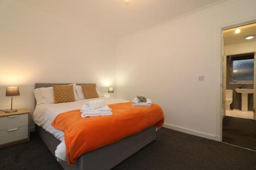 a bedroom with a bed with an orange blanket at Signature - Carrick View in Cumbernauld