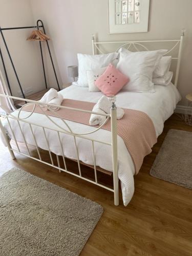 a white bed with white pillows and a pink pillow at Leafy lodge in Lytham in Brown Moss Side