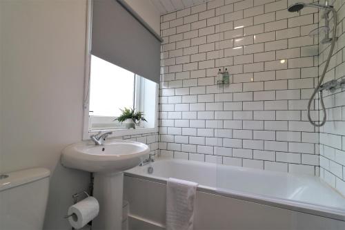 a white bathroom with a sink and a bath tub at Signature - Caldercruix House in Caldercruix