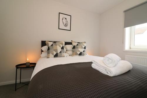 a bedroom with a bed with towels on it at Signature - Caldercruix House in Caldercruix