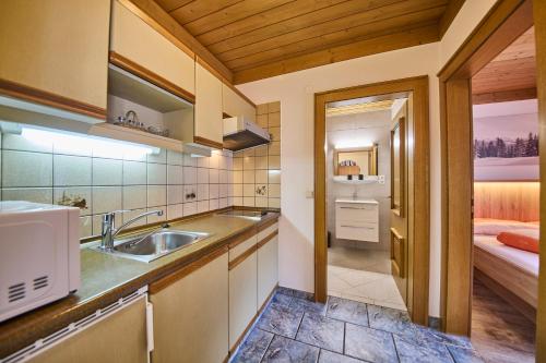 uma cozinha com um lavatório e uma cama num quarto em Landhaus Eichenhof em Saalbach Hinterglemm
