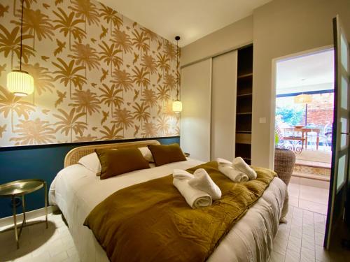 une chambre avec un grand lit avec des serviettes dessus dans l'établissement L'improbable rendez-vous, à Montauban