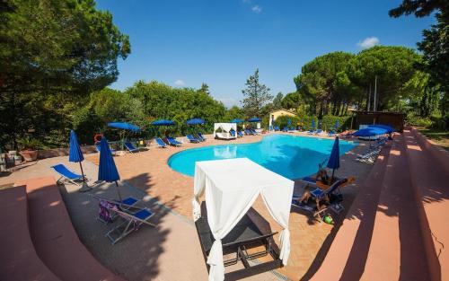 a swimming pool with chairs and blue umbrellas at Holiday Travel Genius at Toscana Holiday Village Camping in San Romano
