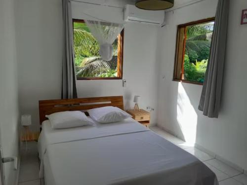 a bedroom with a white bed and two windows at Bungalow Abricot in Petit-Bourg