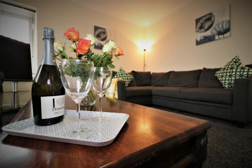 a bottle of wine and two glasses on a table at Signature - Kirkhill House in Kirkmuirhill