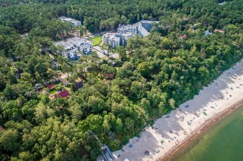 eine Luftansicht auf einen Strand mit Bäumen und Gebäuden in der Unterkunft Grand Laola Spa in Pobierowo