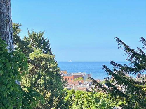 a view of the ocean from behind some trees at LESPARISNORMANDS - le bon pressoir de Villers in Villers-sur-Mer