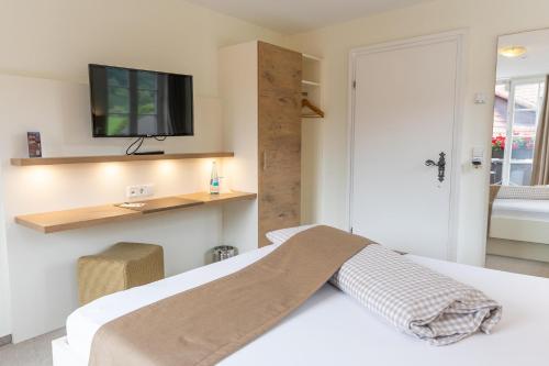 a bedroom with a bed with a tv on the wall at Hotel-Gasthaus Goldener Engel in Glottertal