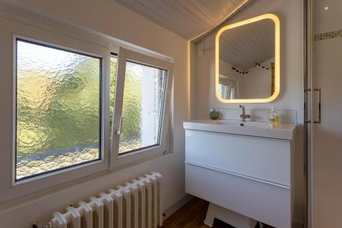 uma casa de banho com um lavatório, um espelho e uma janela em Maison Névez Campagne Calme Piscine em Clohars-Fouesnant