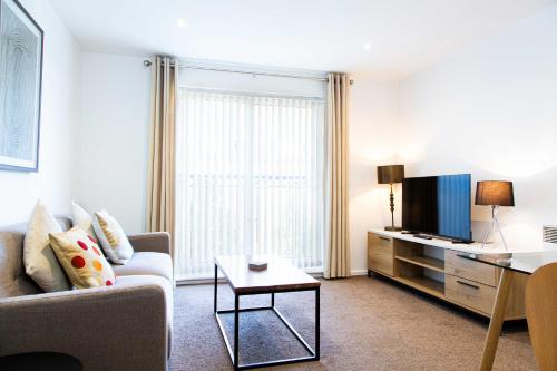 a living room with a couch and a tv at Executive 2 Bed Apartment with Free Parking by Amazing Spaces Relocations Ltd in Warrington