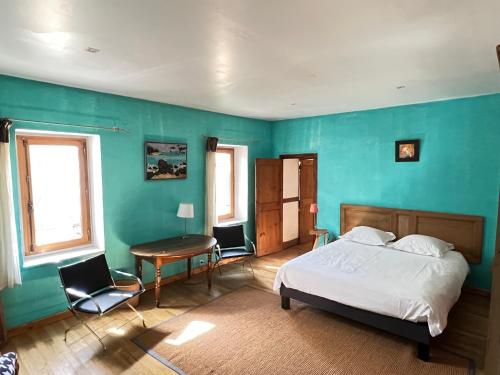 a bedroom with a bed and a table and chairs at Chambres d'Hôtes Les Tapies in Agen dʼAveyron