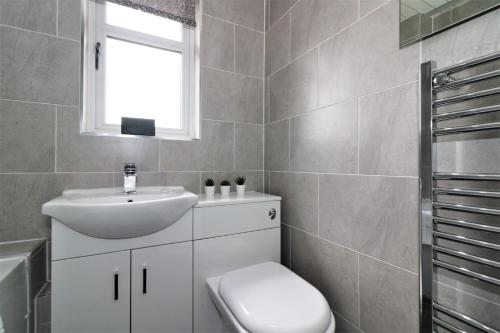 a bathroom with a sink and a toilet and a window at Signature - Culzean House in Newarthill