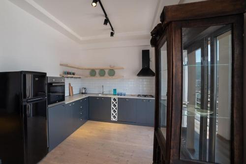 uma cozinha com armários azuis e um frigorífico preto em Night-sight Apt em Tbilisi