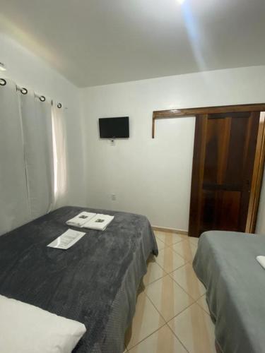 a room with two beds and a tv on the wall at Suites da Rota - Pomerode SC in Pomerode