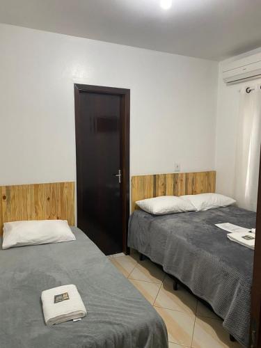 a room with two beds and a door in it at Suites da Rota - Pomerode SC in Pomerode