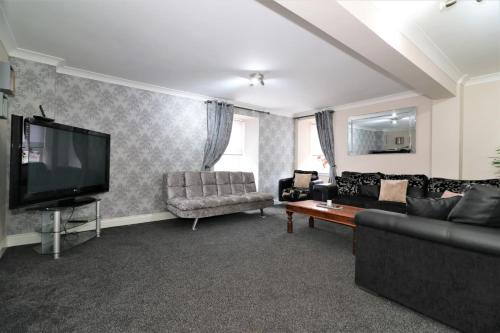 a living room with a couch and a flat screen tv at Signature - Kirkhill Lower in Kirkmuirhill