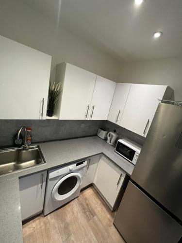 una cucina con armadi bianchi, lavandino e lavastoviglie di 3 Bedroom Flat in King’s Cross, St Pancras’s. 2 minutes to Euston. a Londra