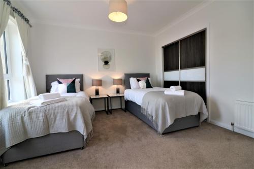 a bedroom with two beds and a window at Signature - Macneish House East Kilbride in East Kilbride