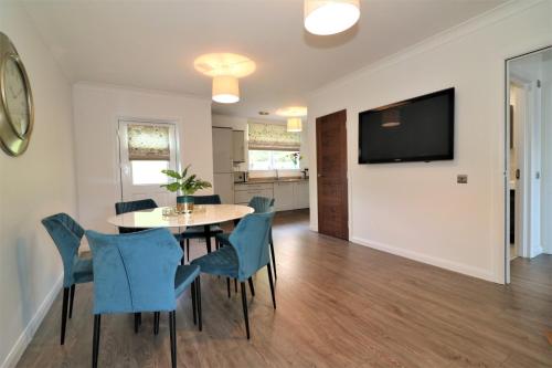 uma sala de jantar com uma mesa e cadeiras e uma televisão em Signature - Macneish House East Kilbride em East Kilbride