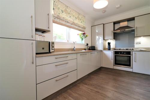 a white kitchen with white cabinets and a window at Signature - Macneish House East Kilbride in East Kilbride
