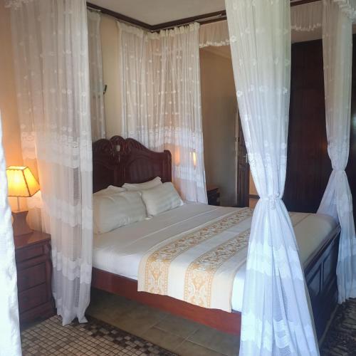 a bedroom with a bed with white curtains at North Coast Beach Hotel in Kikambala