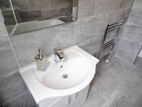 La salle de bains est pourvue d'un lavabo blanc et d'une baignoire. dans l'établissement Signature - Langlands House, à Glasgow