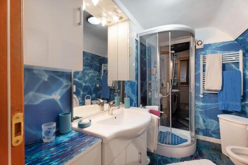 y baño azul y blanco con lavabo y ducha. en Casa del sole, en Toceno