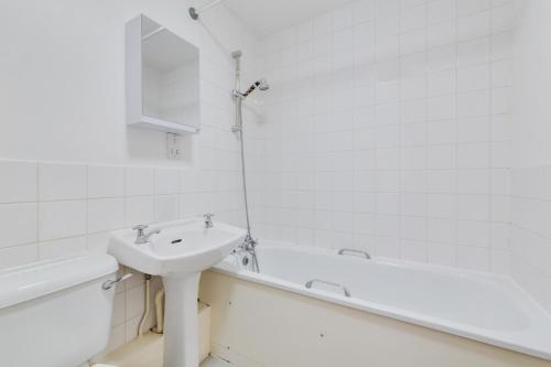 un bagno bianco con lavandino e vasca di Cosy 1 Bed Apartment - Canary Wharf, Limehouse a Londra
