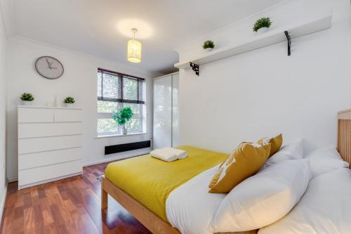 una camera da letto con un grande letto con una coperta gialla di Cosy 1 Bed Apartment - Canary Wharf, Limehouse a Londra