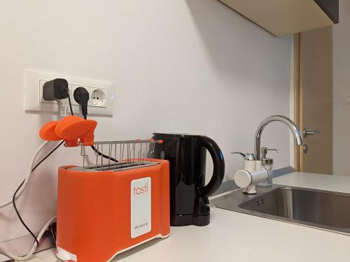 an orange appliance sitting on a kitchen counter next to a sink at Petite Studio With Ensuite Bathroom in Zagreb