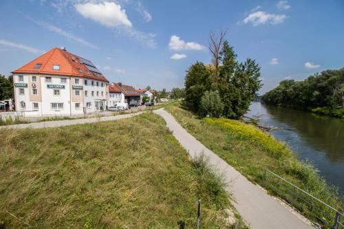 a building with a red roof next to a river at Gasthof zur Länd in Moosburg